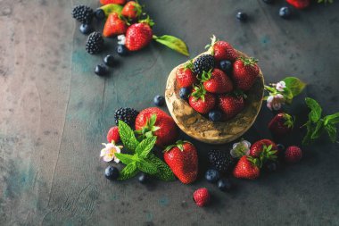 taze böğürtlen, yaban mersini, çilek ve gri yüzeyde yeşil nane yaprakları yakın çekim görünümü