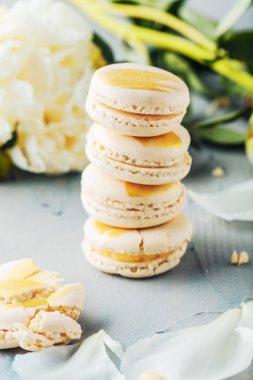 ahşap yüzeyde lezzetli Fransız makarna kurabiye ve beyaz çiçekler in yakın çekim görünümü 