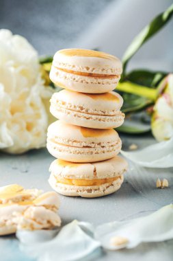 ahşap yüzeyde lezzetli Fransız makarna kurabiye ve beyaz çiçekler in yakın çekim görünümü