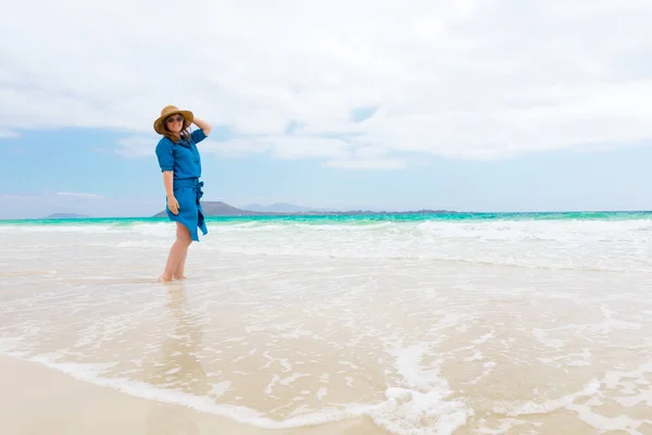 Happy traveller woman in blue dress enjoying tropical beach vacation