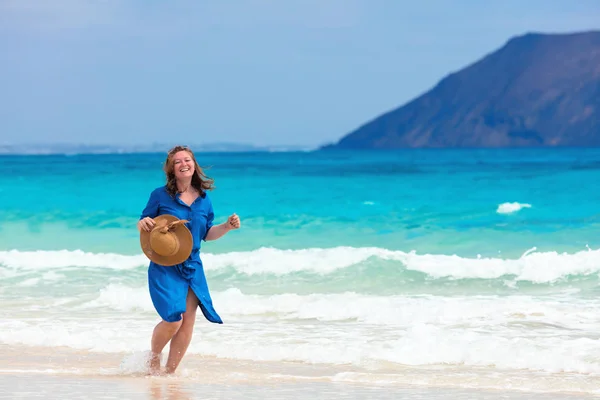 Happy traveller woman in blue dress enjoying tropical beach vacation