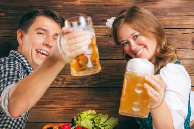 mutlu genç çift bira bardak tutan ve kamera, oktoberfest kavramı gülümseyerek