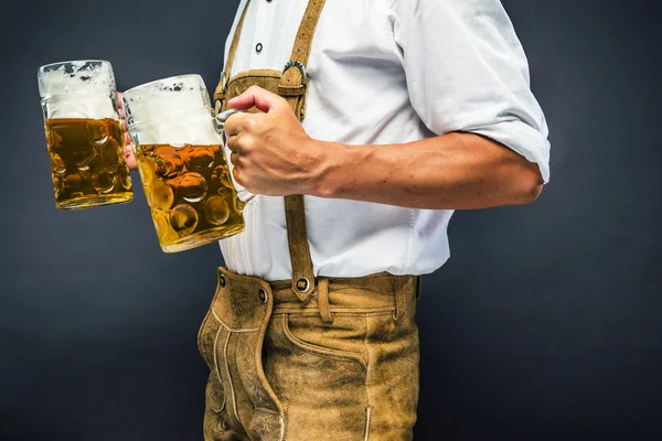 オクトーバーフェストビールのマグカップを持つ伝統的なバイエルンの服を着た男のトリミングショット — ストック写真