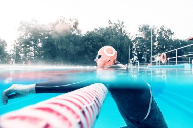açık yüzme havuzunda dinlenen profesyonel orta yaşlı sporcunun yan görünümü
