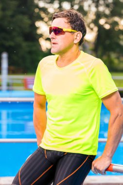 yakışıklı atletik orta yaşlı yüzücü uzak açık yüzme havuzu yakınında bakıyor