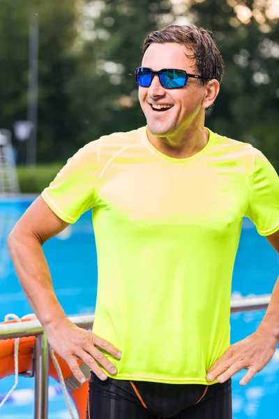 açık yüzme havuzu yakınında bel elleri ile duran neşeli atletik erkek yüzücü