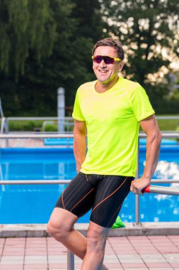 açık yüzme havuzu yakınında gülümseyen atletik orta yaşlı yüzücü 