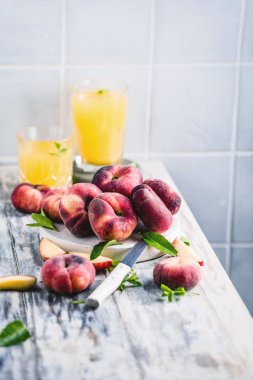 ahşap masa üzerinde yeşil yaprakları ve meyve suyu bardak ile taze olgun şeftali yakın çekim görünümü   