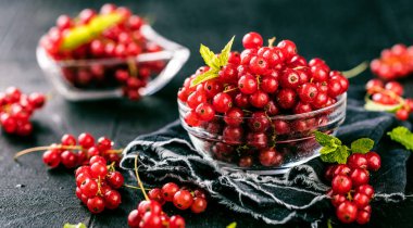 koyu ahşap masa üzerinde taze olgun kırmızı kuş üzümü yakın çekim görünümü 