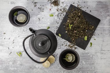 gri yüzeyde bardak ile siyah çaydanlık üst görünümü