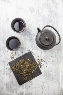 gri yüzeyde bardak ile siyah çaydanlık üst görünümü