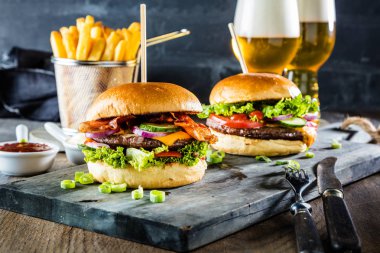 gurme hamburgerler, patates kızartması ve masada bira bardağı  