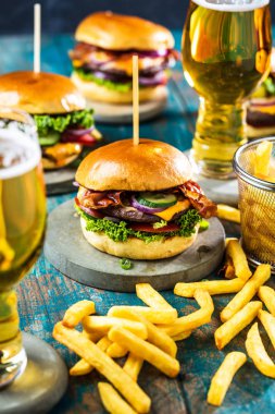gurme hamburgerler, patates kızartması ve masada bira bardağı  