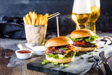 lezzetli hamburger, patates kızartması ve masada bira gözlük yakın çekim görünümü  