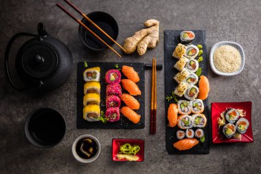 Chopsticks, zencefil, soya sosu ve su ısıtıcısı ile arduvaz panoları üzerinde set lezzetli suşi üst görünümü