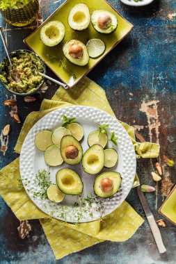 taze yarıya avokado, dilimlenmiş Limes ve otlar masada üst görünümü