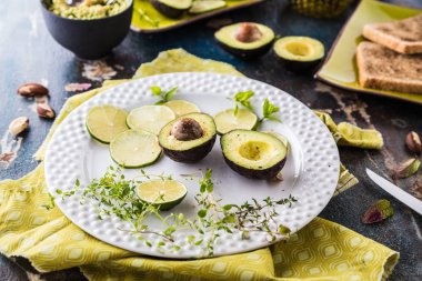 taze yarıya avokado, dilimlenmiş kireç ve otlar yakından görünümü