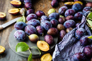 ahşap masa üzerinde taze olgun organik mor erik ve yeşil yaprakları üst görünümü