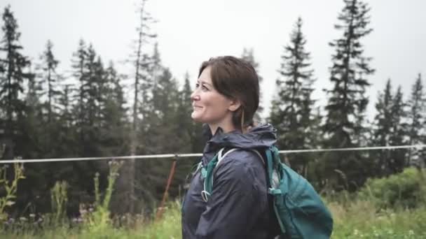 霧の日に美しい山の中でバックパックハイキングをしている若い女性 — ストック動画