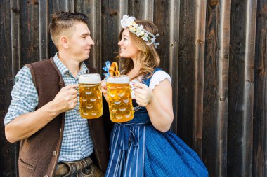 mutlu genç çift bira kupaları tutan ve birbirlerine gülümseyen, oktoberfest kavramı, oktoberfest kavramı 
