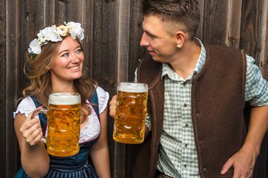 bavyera kostümleri mutlu genç çift bira bardakları tutan ve birbirlerine gülümseyen, oktoberfest kavramı