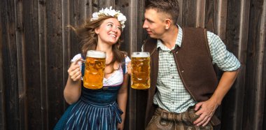 bira bardakları tutan Bavyera kostümleri mutlu genç çift, oktoberfest kavramı
