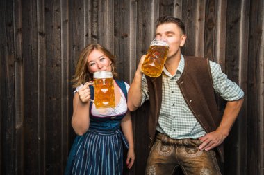 bira bardakları tutan Bavyera kostümleri mutlu genç çift, oktoberfest kavramı