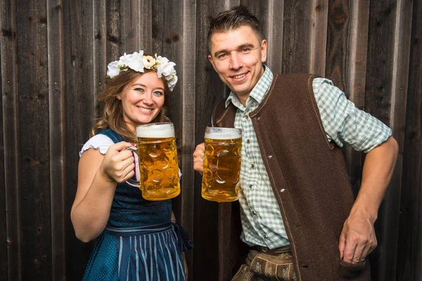 mutlu genç çift bira kupaları tutan ve kamera, oktoberfest kavramı gülümseyerek 