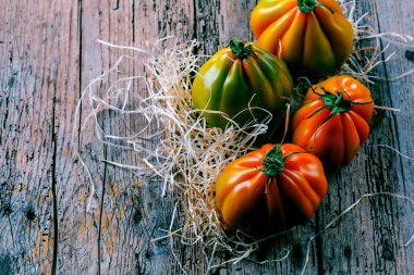 Tahta masadaki taze organik Oxheart domateslerinin yakın plan görüntüsü.