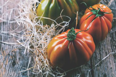 Tahta masadaki taze organik Oxheart domateslerinin yakın plan görüntüsü.