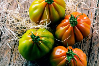 Tahta masadaki taze organik Oxheart domateslerinin yakın plan görüntüsü.