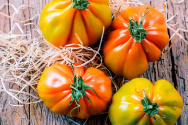 Tahta masadaki taze organik Oxheart domateslerinin yakın plan görüntüsü.