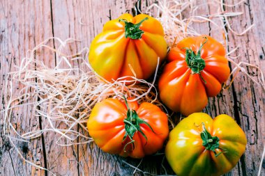 Tahta masadaki taze organik Oxheart domateslerinin yakın plan görüntüsü.