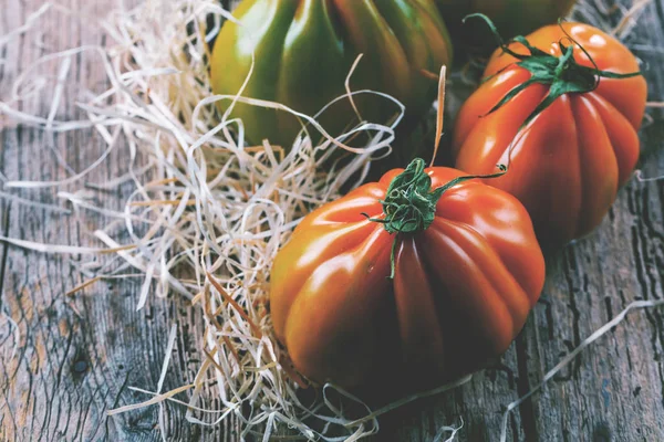 Tahta masadaki taze organik Oxheart domateslerinin yakın plan görüntüsü.