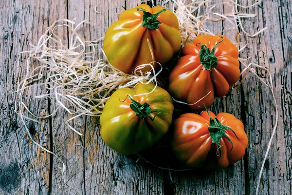 Tahta masadaki taze organik Oxheart domateslerinin yakın plan görüntüsü.