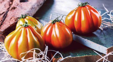 Tahta masadaki taze organik Oxheart domateslerinin yakın plan görüntüsü.