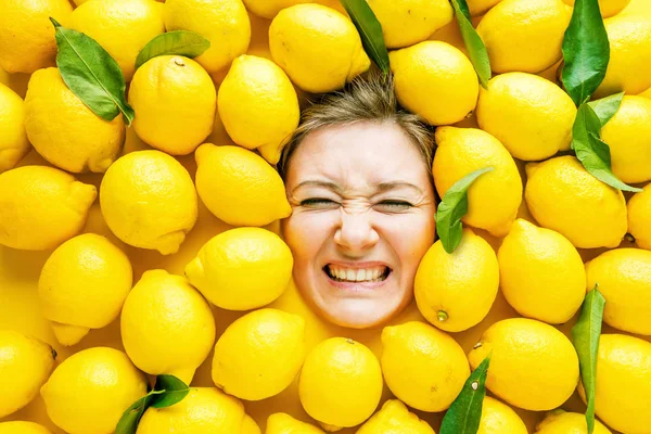 Woman with lemons, concept for food industry. Face of laughing woman in lemon surface