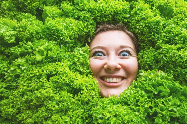 Woman with salad leaves, concept for food industry. Face of laughing woman in salad area.