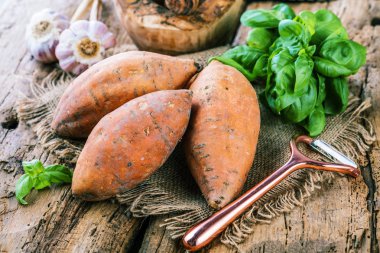 ahşap masada fesleğen yaprakları ile lezzetli sağlıklı bütün tatlı patates yakın çekim görünümü