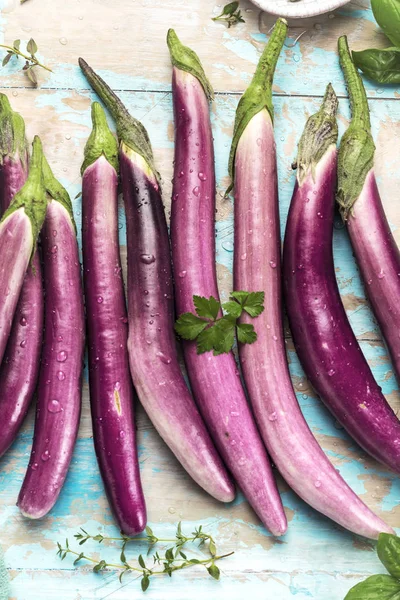 top view of fresh purple japanese eggplants on rustic colored wooden background