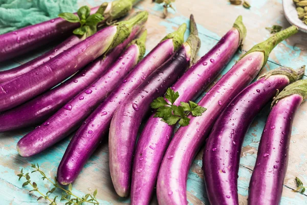top view of fresh purple japanese eggplants on rustic colored wooden background
