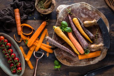 ahşap masada taze çiğ gökkuşağı havuç ve domates üst görünümü