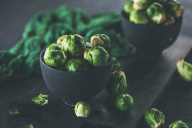 Tabaklarda taze Brüksel lahanaları ve masada yeşil kumaşların yakın plan görüntüsü.