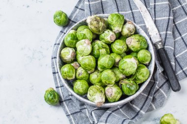 Sağlıklı yeşil Brüksel lahanası gri yüzeyde kasede filizleniyor.