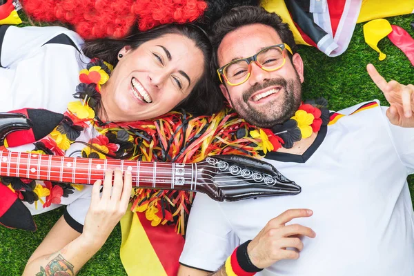 勝利を祝う熱狂的なドイツのスポーツサッカーファン 草の上に横たわるとギターを演奏 — ストック写真