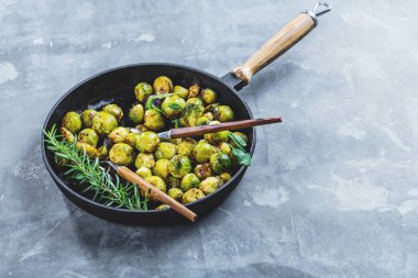 close-up view of healthy brussels sprouts in frying pan on table clipart