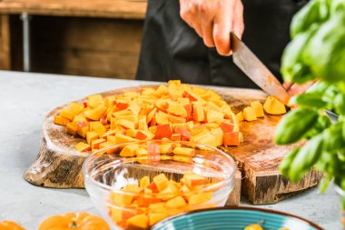 Gemide balkabağı doğrayan bir erkek şef resmi var.