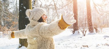 Kış ormanında kollarını açmış mutlu genç bir kadın.