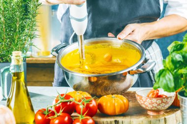 Balkabağı çorbasını karıştırıcıyla hazırlayan kişinin orta bölümü