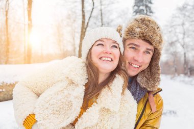 Güzel, mutlu, genç bir çift kış ormanında birbirlerine sarılıyorlar.